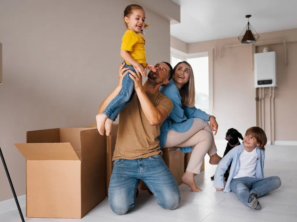 Familia feliz con dos niños y un perro en su nuevo hogar, rodeados de cajas de mudanza